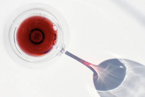 A overview shot of a glass of red wine, with the glass casting a long shadow to the five o'clock position